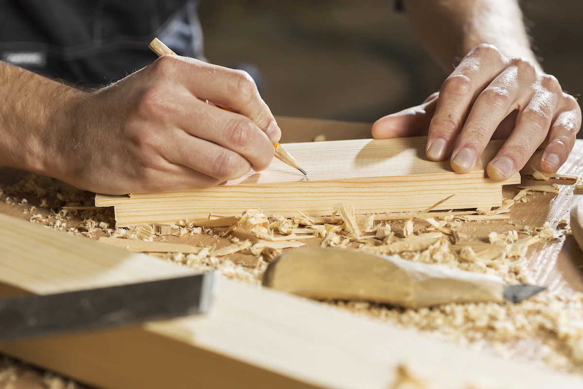 A joiner marking out a length of timber by hand, shavings and a chisel on the bench