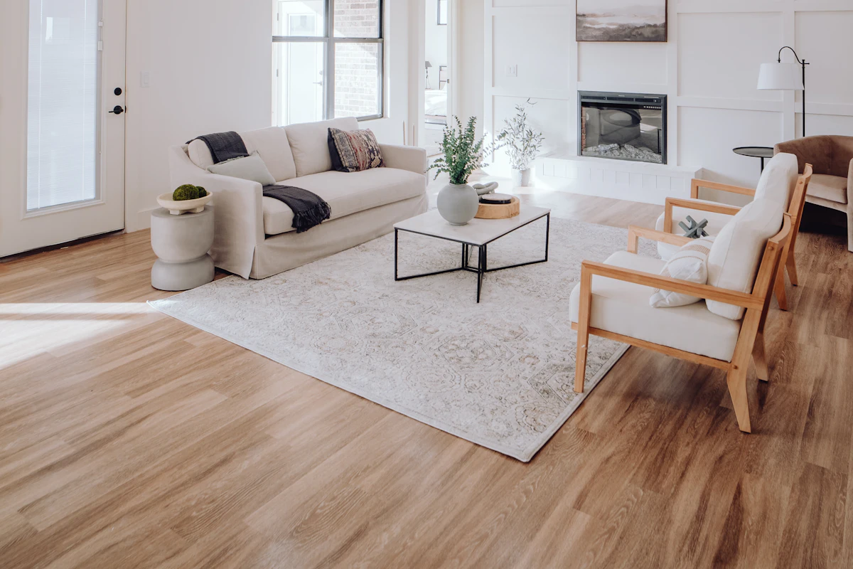 A calm, uncluttered sitting room with pale floorboards and light from three windows